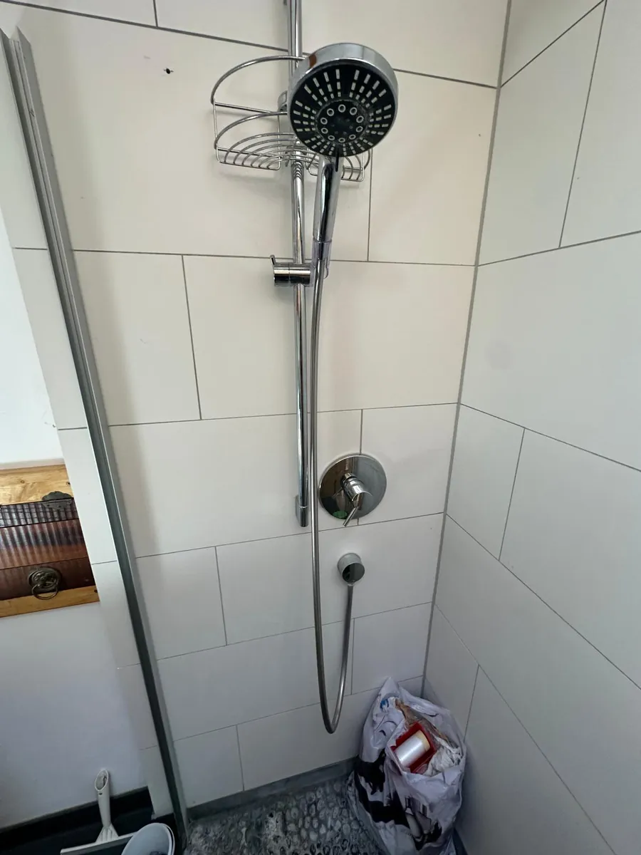 Alte Dusche mit Kieselboden und Duschstange